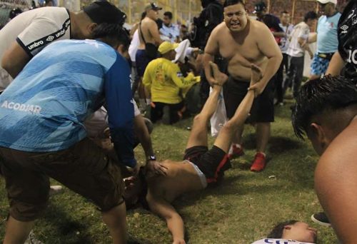 Aficionados ayudan a los heridos tirados en la cancha luego de una estampida en el estadio Cuscatlán en San Salvador. 20 mayo, 2023. Foto: AFP.