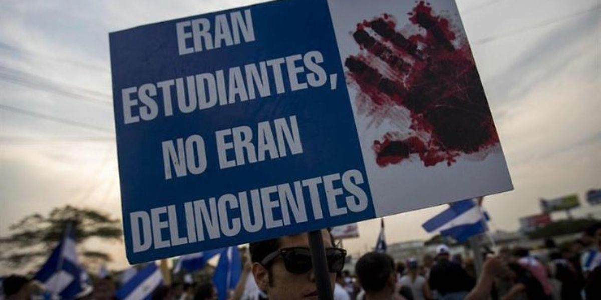 Joven sostiene pancarta con el lema "Eran estudiantes, no eran delincuentes" durante las manifestaciones en Nicaragua en 2018. Foto: Internet.