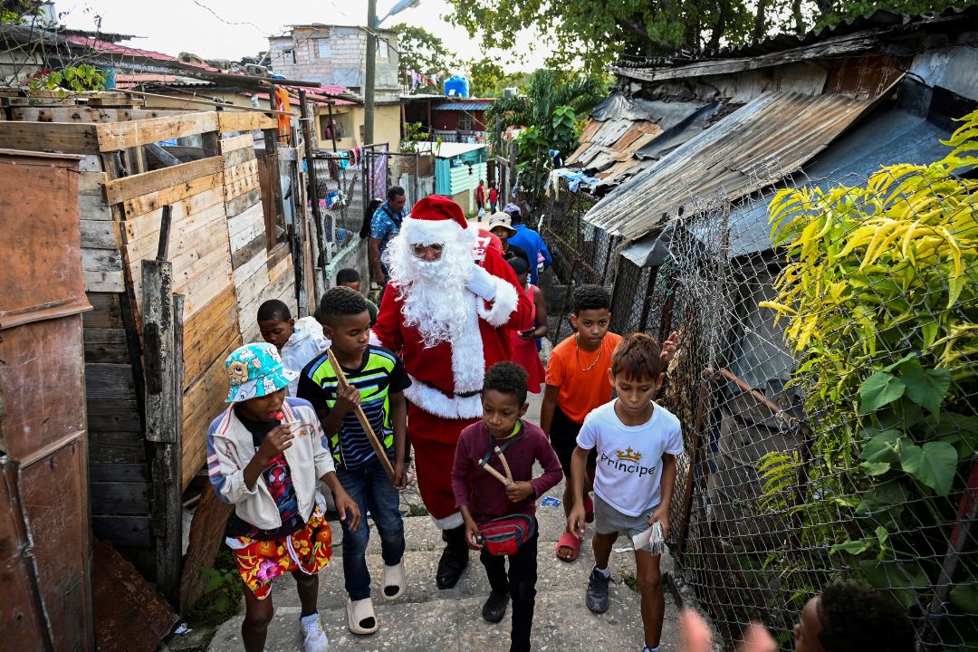 Un hombre vestido de Papá Noel camina con niños por las calles de La Habana el 21 de diciembre de 2023. Foto: Yamil LAGE / AFP.