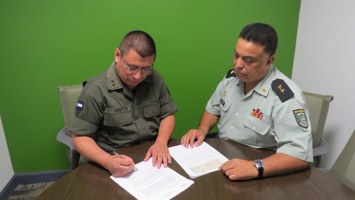 Marvin Antonio Briceño Rivas (derecha) viendo cómo firma el militar García.